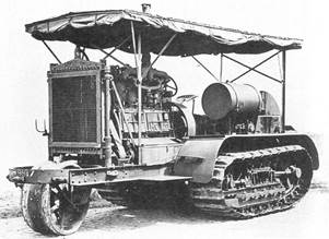 An early bulldozer-like tractor, on crawler tracks, with a leading single wheel  for steering  projecting from the front on an extension to the frame. The large internal combustion engine is in full view, with the cooling radiator prominent at the front. An overall roof is supported by thin rods, and side protection sheeting is rolled up under the edge of the roof.
